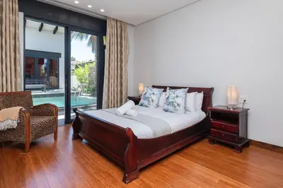 a bedroom with a bed and a chair and a pool at Family home in Tableview, close to Dolphin Beach. in Cape Town