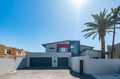 a house with a white fence and a palm tree at Family home in Tableview, close to Dolphin Beach. in Cape Town