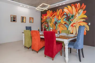 a dining room table with colorful chairs and a painting at Family home in Tableview, close to Dolphin Beach. in Cape Town