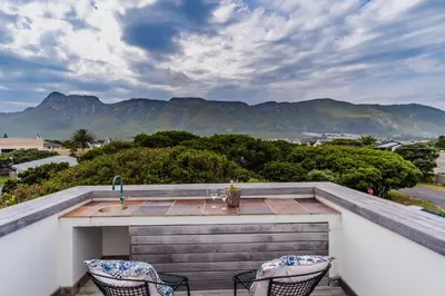 a balcony with a sink and two chairs at 3 on Vermont in Hermanus