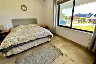 a bedroom with a bed and a large window at Happy Place Pringle Bay for 2 in Pringle Bay