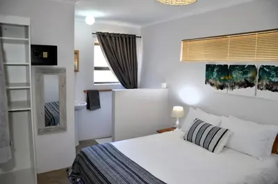 a bedroom with a white bed and a window at The Beach Cottage Betty's Bay in Bettyʼs Bay