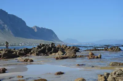 a person standing on the rocks on the beach at The Beach Cottage Betty's Bay in Bettyʼs Bay