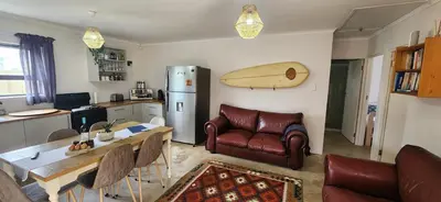 a kitchen with a table and a surfboard on the wall at The Beach Cottage Betty's Bay in Bettyʼs Bay