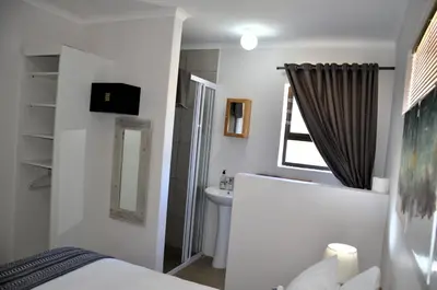 a bathroom with a bed and a sink and a mirror at The Beach Cottage Betty's Bay in Bettyʼs Bay