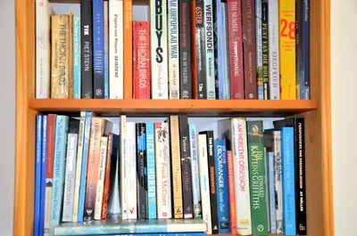 a book shelf filled with lots of books at The Beach Cottage Betty's Bay in Bettyʼs Bay