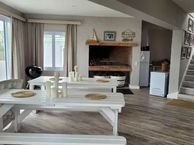 a living room with white tables and a fireplace at Nest Egg Holiday Home Voëlklip in Hermanus