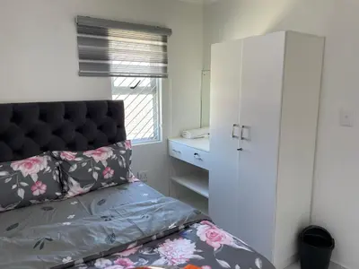 a small bedroom with a bed and a white cabinet at The MK House in Cape Town