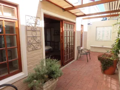 an open door to a patio with chairs and plants at Belle View Guest Suite in Hermanus