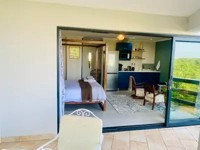 a bedroom with a bed and a view of a kitchen at Salt Shore Studios in Hermanus