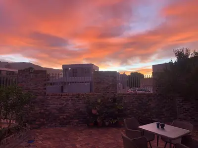 a sunset over a patio with a table and chairs at Salt Shore Studios in Hermanus