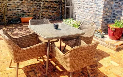 a table with wicker chairs sitting on a patio at Salt Shore Studios in Hermanus