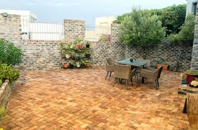 a patio with a table and chairs and a brick wall at Salt Shore Studios in Hermanus