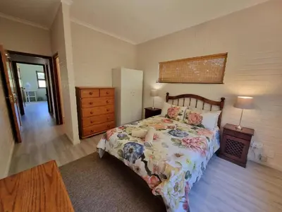 a bedroom with a bed and a dresser and a drawer at Milkwood Cottage in Bettyʼs Bay