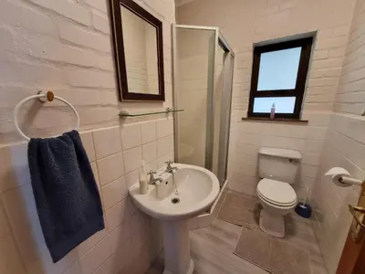 a white bathroom with a sink and a toilet at Milkwood Cottage in Bettyʼs Bay
