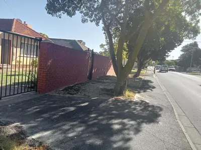 a fence with a tree on the side of a street at ATHOME BELLVILLE Chrismar in Cape Town