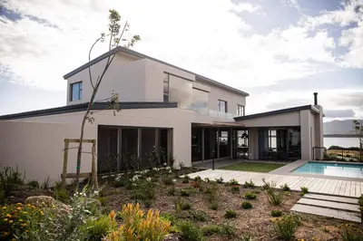 a white house with a pool in front of it at Benguela Cove - Milk and Honey in Hermanus