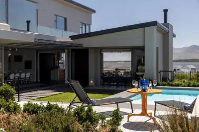 a patio with a table and chairs next to a pool at Benguela Cove - Milk and Honey in Hermanus