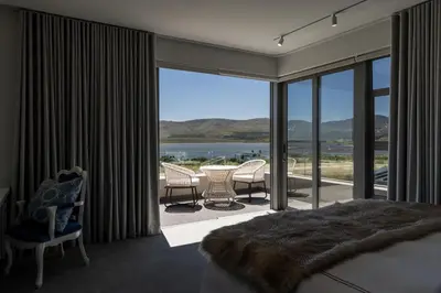 a bedroom with a bed and a balcony with a view at Benguela Cove - Milk and Honey in Hermanus