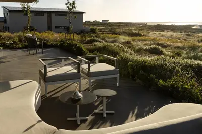 a patio with two chairs and a table at Benguela Cove - Milk and Honey in Hermanus