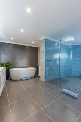 a bathroom with a tub and a shower with blue tiles at The Fuchsia Collection in Somerset West