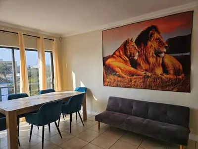 a dining room with a table and a painting of lions at Strand Beach Apartment in Cape Town