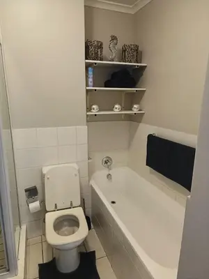 a white bathroom with a toilet and a bath tub at Nautica3 in Cape Town