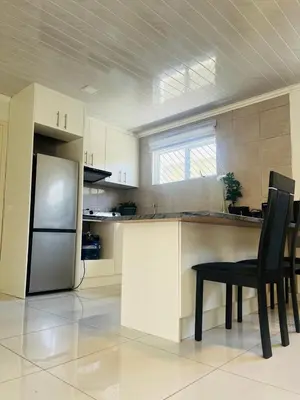 a kitchen with a refrigerator and a table and chairs at The MK House in Cape Town
