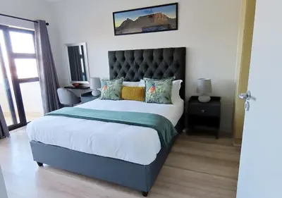 a bedroom with a large bed with a black headboard at Cape Town Luxury Stays Knightsbridge Luxury Apartment Century City in Cape Town