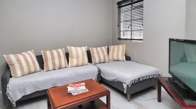 a living room with a couch and a table and a tv at Corner View in Paarl