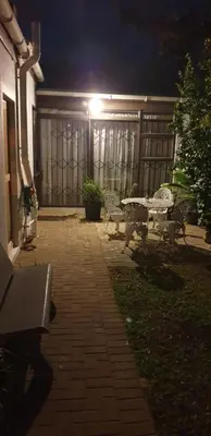 a patio at night with benches and a fence at Hibiscus B&B in Strand