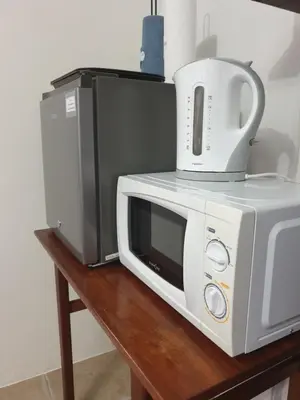 a microwave and a toaster oven sitting on a table at Hibiscus B&B in Strand
