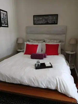 a large bed with red pillows and a tray on it at Rusticana Room1 in Cape Town