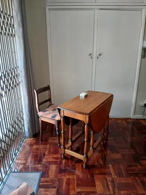 a wooden table and a chair in a room at Rusticana Room1 in Cape Town