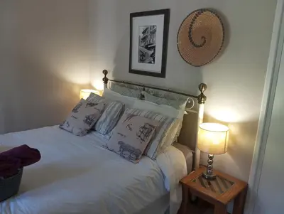 a bedroom with a white bed with pillows and a lamp at Rusticana in Cape Town
