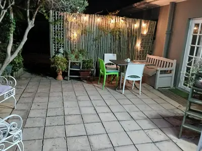 a patio with chairs and a table and a fence at Rusticana in Cape Town