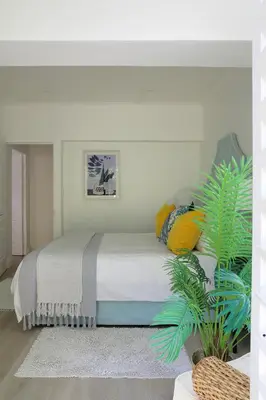 a bedroom with a bed with colorful pillows and a plant at Best of Both! Mountain and Sea View Home. in Hermanus