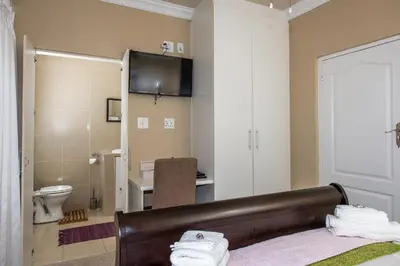 a bedroom with a bed and a bathroom with a toilet at Guesthouse De Tijger Lodge in Parow