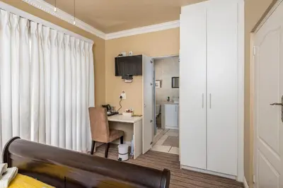 a bedroom with a desk and a chair in a room at Guesthouse De Tijger Lodge in Parow