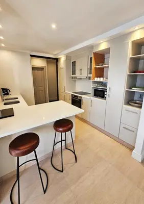 a kitchen with a white counter and two stools at Casa La Vista in Somerset West