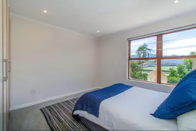 a bedroom with a bed and a large window at Beachfront Bliss at Malgas Views in Gordonʼs Bay