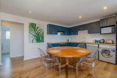 a kitchen with a wooden table and chairs in a kitchen at Beachfront Bliss at Malgas Views in Gordonʼs Bay