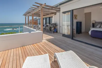 a house with a balcony with a bedroom and the ocean at Le Paradis Penthouse in Hermanus