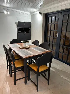 a dining room table with chairs and a television at Addai Self Catering Brackenfell Durbanville area in Cape Town