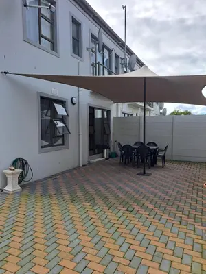 a patio with tables and an umbrella in front of a building at Casa Table View in Cape Town