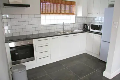 a white kitchen with a sink and a microwave at Lazy Days Apartments - Cape Town in Cape Town