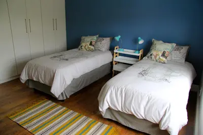 a bedroom with two beds and a blue wall at Lazy Days Apartments - Cape Town in Cape Town
