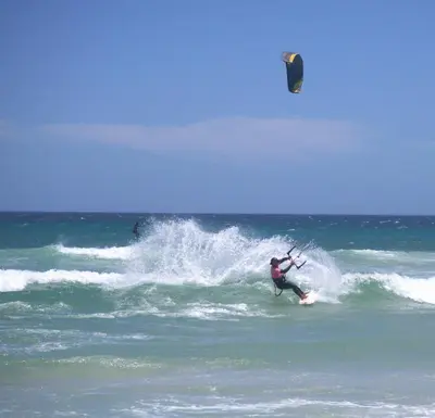 a man riding a wave in the ocean with a kite at The Kite Villa - Luxury Kitesurfing Guesthouse in Cape Town