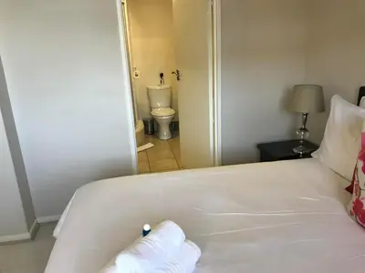 a white bed with a towel on it in a bedroom at The Island Club Apartment in Cape Town