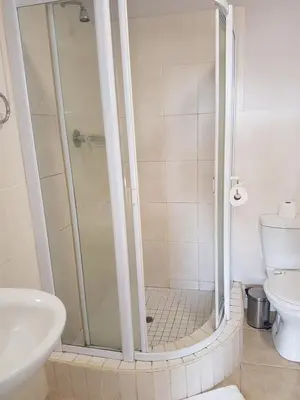 a bathroom with a shower with a toilet and a sink at The Island Club Apartment in Cape Town